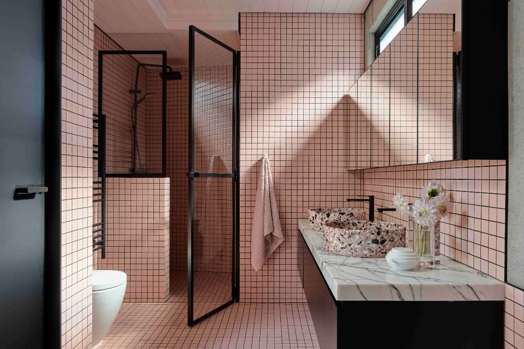 A bathroom scene tastefully decorated in pink and black tiles, inspiration for a barbiecore interior.